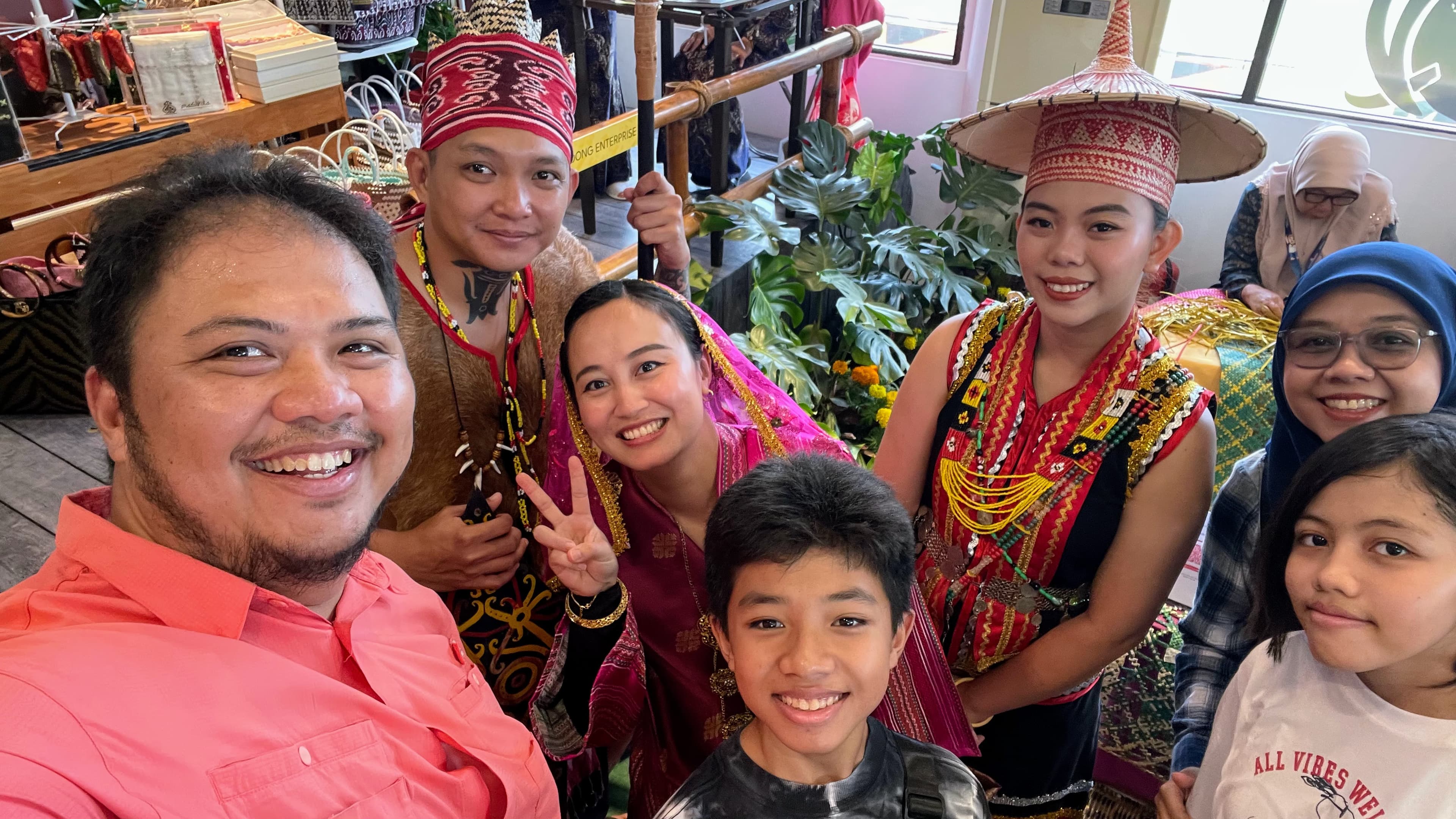 Us with a cheerful Sarawakian group proudly showcasing their traditional attire at the Sarawak Pavilion.
